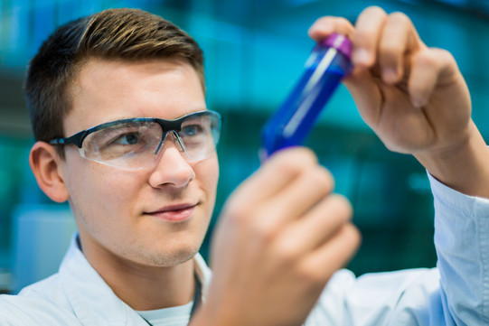 A researcher holds a sample vessel in his hand.