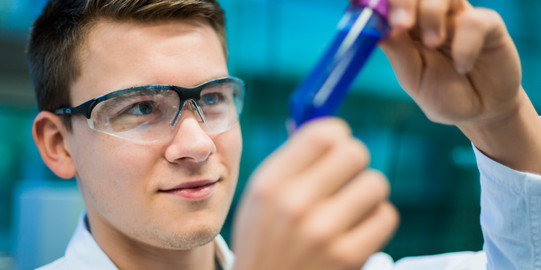 A researcher holds a sample vessel in his hand.