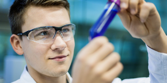 A researcher holds a sample vessel in his hand.