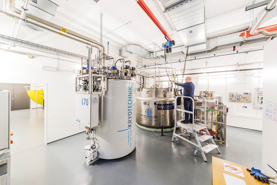 A laboratory with a large white container for Kyrotechnics and a metal container, a man is standing on a ladder.