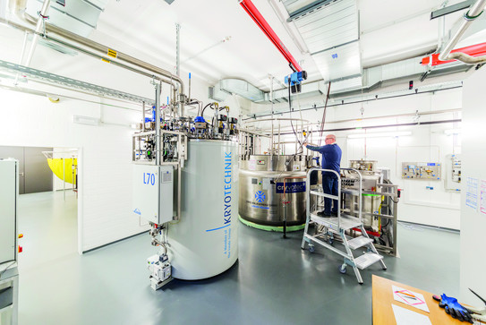 A laboratory with a large white container for Kyrotechnics and a metal container, a man is standing on a ladder.